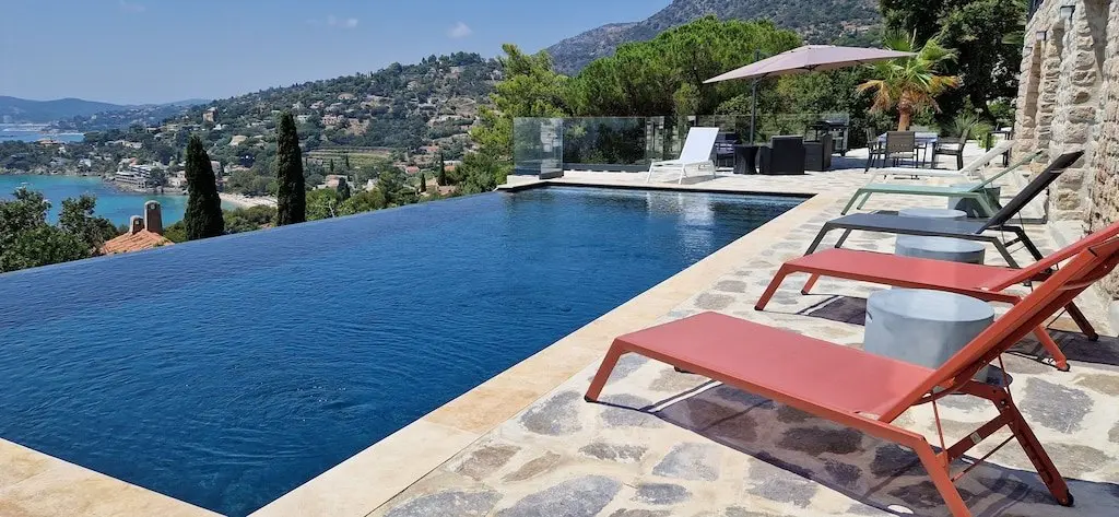 Piscine à débordement de la Villa GL. et transats rouges, face à la mer
