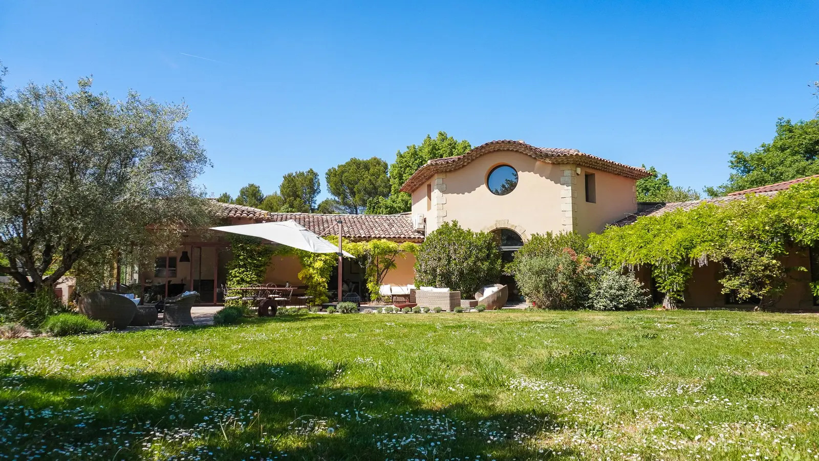 Façade de la Villa S. et son jardin, avec un parasol sur la terrasse